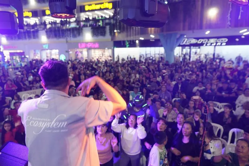 Presentador animando al público frente a la tarima entre luces moradas