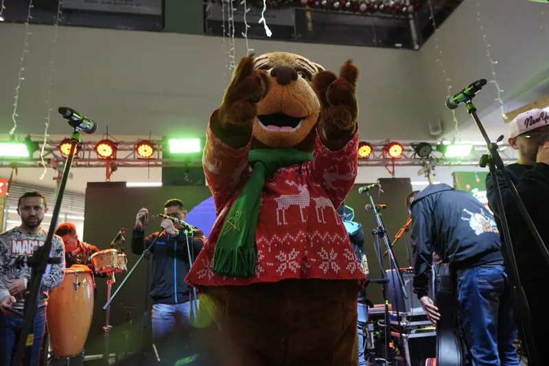 Mascota navideña celebrando en la tarima junto a la banda