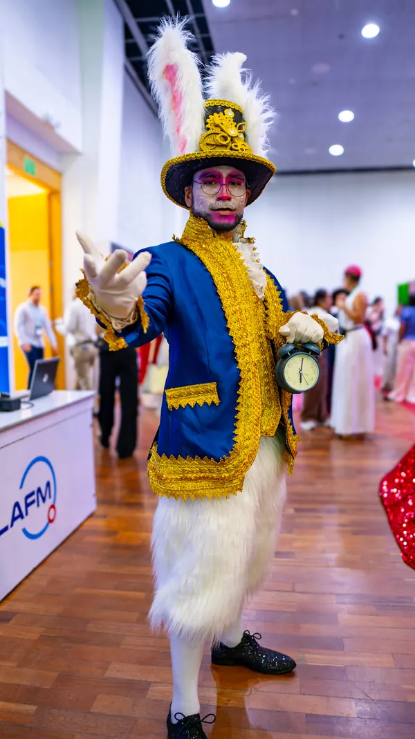Personaje de sombrerero con traje azul y dorado recorriendo los pasillos