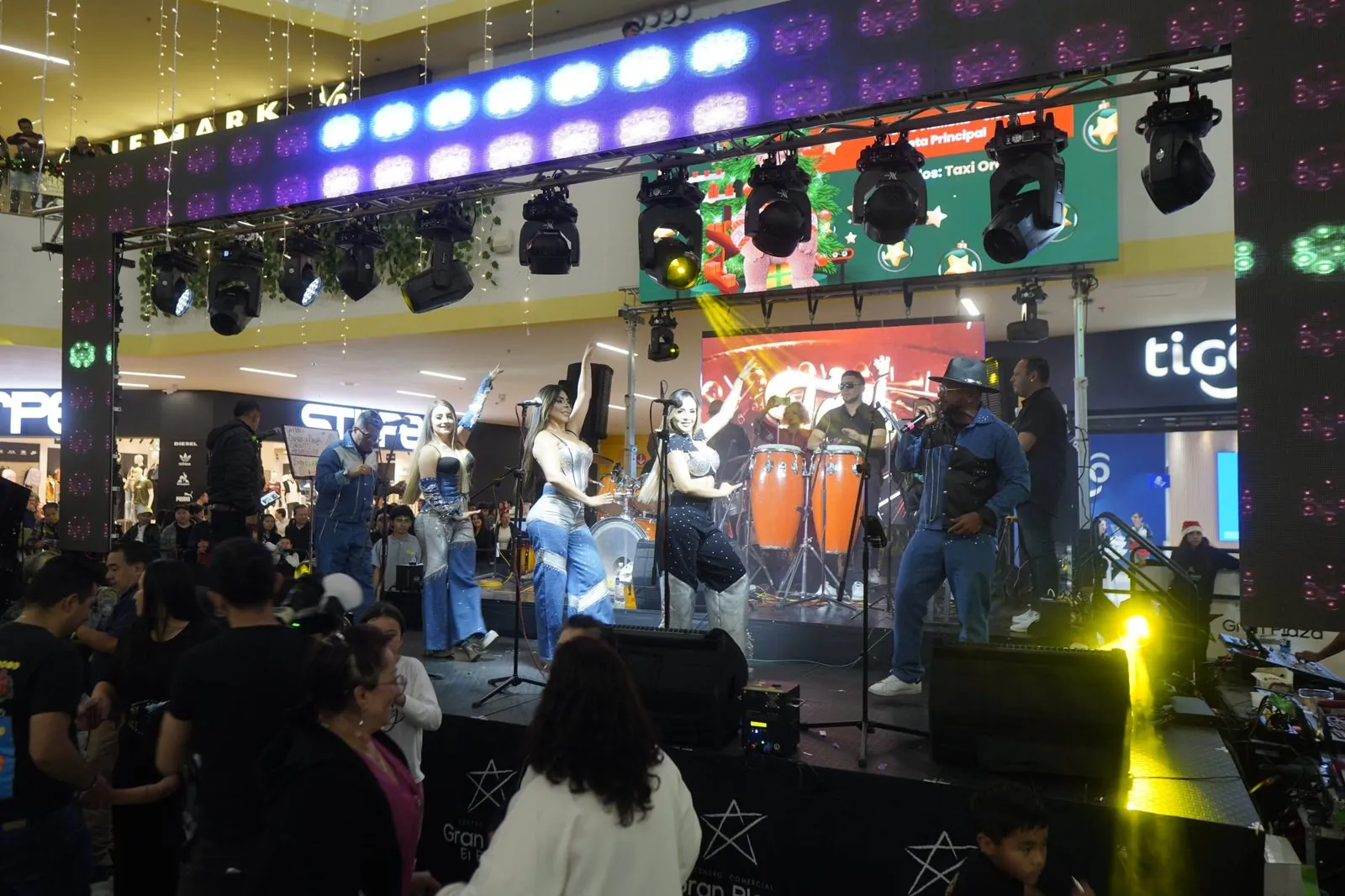 Orquesta en tarima con chispas frías durante la inauguración de Navidad y el atrio lleno