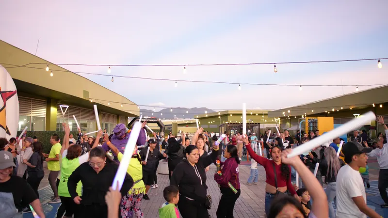Público bailando con tubos LED al atardecer en la plazoleta